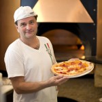 Pizza chef showing off one of his creations at Roostica Wood-fire Pizzeria